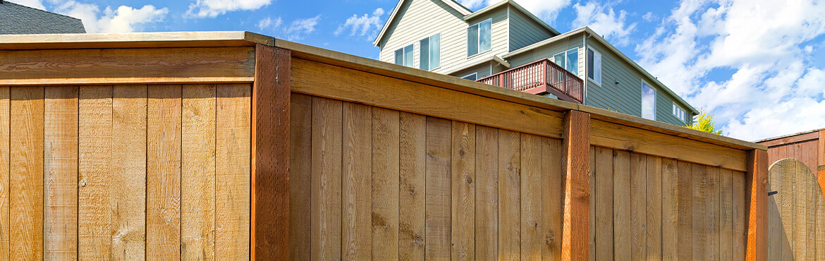 Close up wood fencing with house in background.